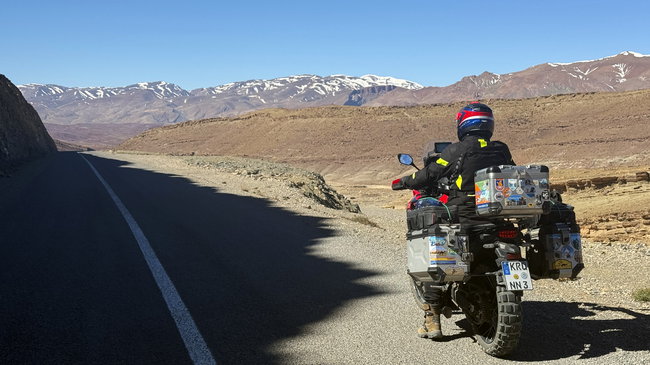 Voyage moto MM10 – Descente depuis un col élevé de l'Atlas Descente sur une route sinueuse vers une vallée montagneuse isolée
